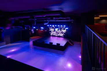 A small modern stage with blue lighting and graffiti backdrop.