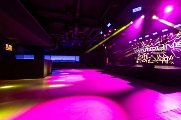 Empty nightclub with purple and yellow lights.