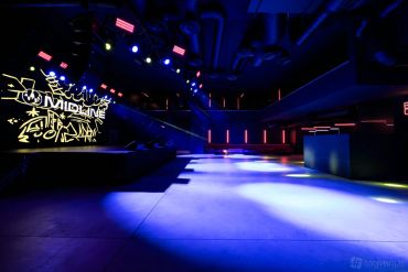 Empty nightclub with colorful lights and graffiti.