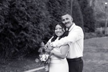 Smiling couple embracing outdoors, the woman holding flowers.