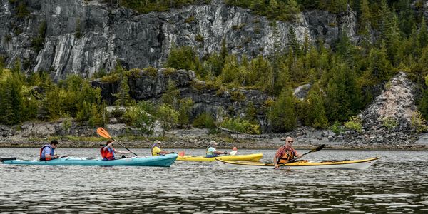 Guests and their guide kayaking along the base of cliffs among the ruins of an historic lime quarry
