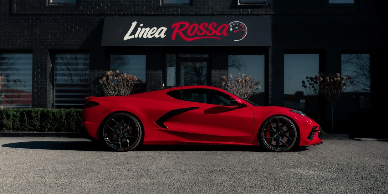 Red sports car parked in front of Linea Rossa building.