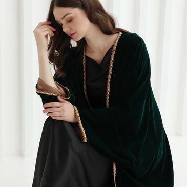 Woman in a black dress and dark green shawl with gold trim.