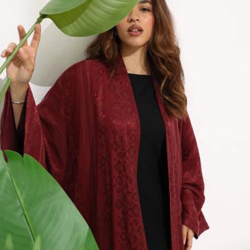 Woman wearing a maroon outfit holding green leaves.
