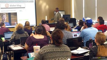 Classroom with a lecturer and attentive students using laptops.