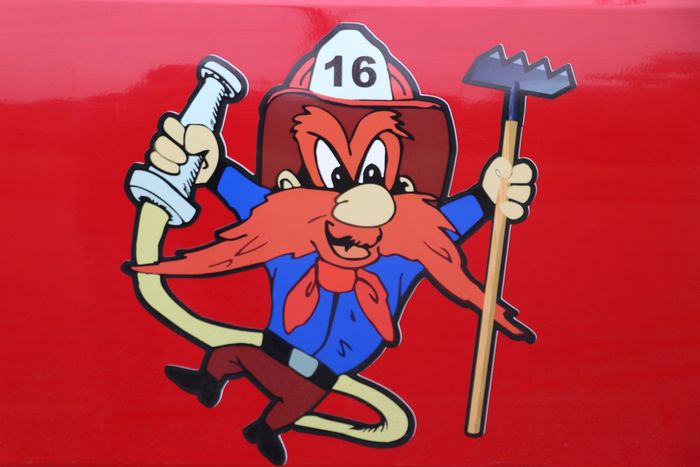 Cartoon firefighter with a red beard holding a hose and a tool on a red background.
