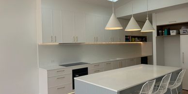 Modern kitchen with white cabinets, island, and pendant lights.