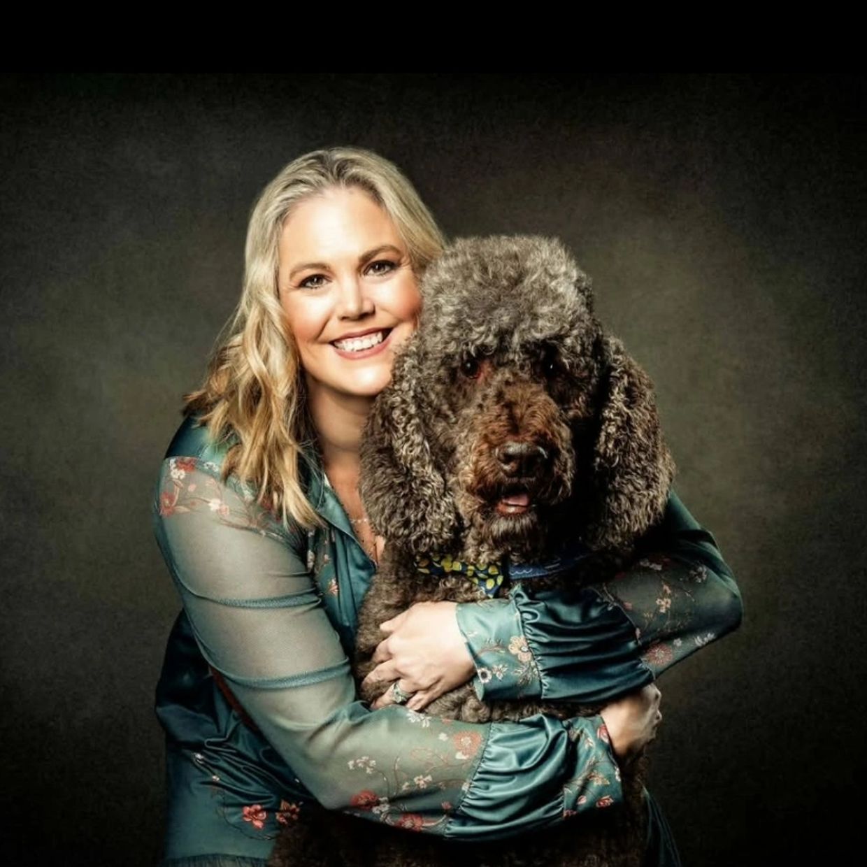 Woman hugging her large curly-haired dog.