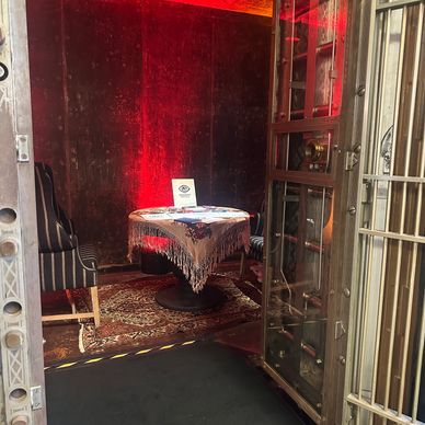 A small table with a lace tablecloth and a chair in a dimly lit room with red lighting.