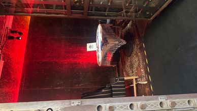 A small table with a lace tablecloth and a chair in a dimly lit room with red lighting.