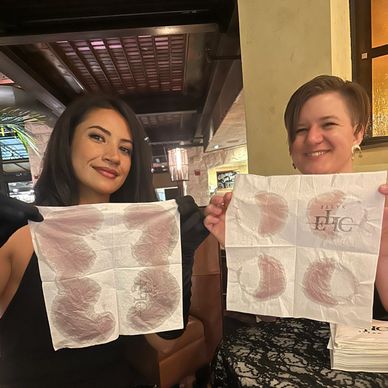 Two women showing napkins with lipstick marks.