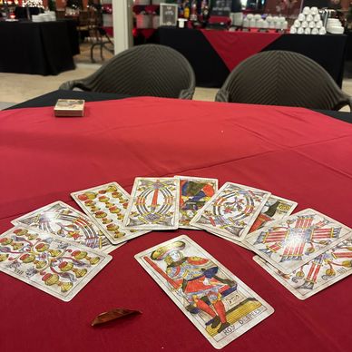 Tarot cards spread on a red tablecloth with chairs in the background.