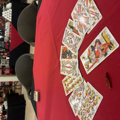 Tarot cards spread on a red tablecloth with chairs in the background.