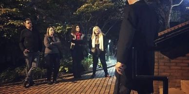 A storyteller conducts an outdoor walking tour of haunted locations. 