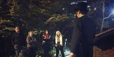 A storyteller conducts an outdoor walking tour of haunted locations. 
