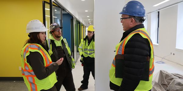 Construction workers wearing safety gear discussing on site.