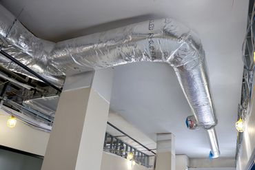 Large insulated HVAC duct running along a ceiling in a building under construction.