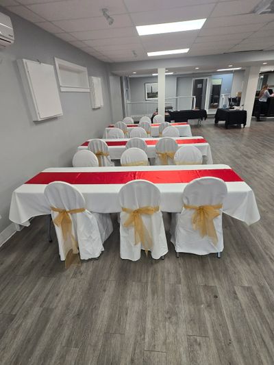 Event room with tables and chairs decorated in white, red, and gold.
