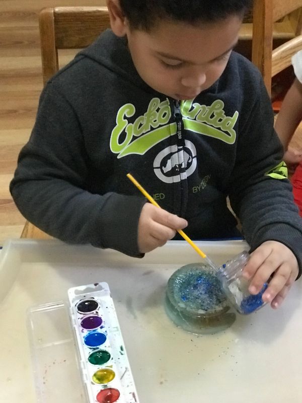3 year old painting the ice with glitter and water color.