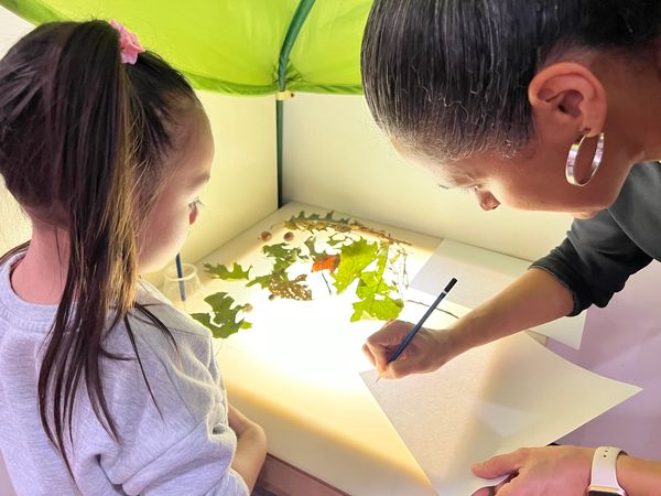 Writing the preschoolers name on the paper while at the light table. 