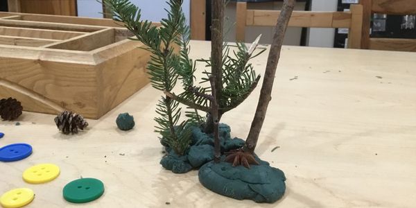 Children playing with playdough and loose parts created Christmas trees.