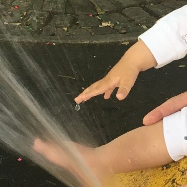 Child playing with water stream.