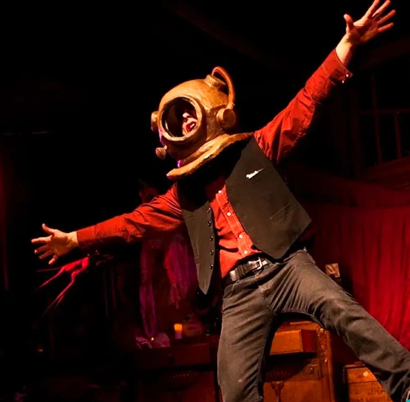 Person in vintage diving helmet theatrically posing on stage.