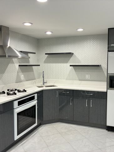 Modern kitchen with grey cabinets and white countertops.