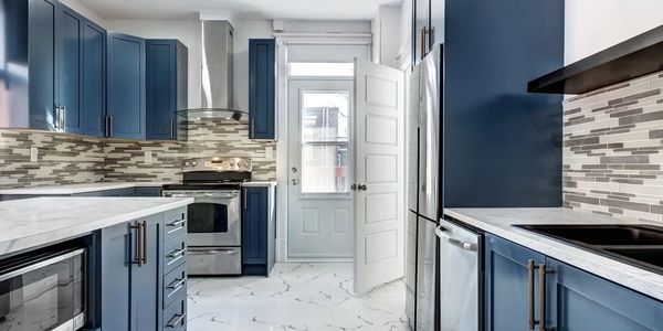 Modern kitchen with blue cabinets and white marble flooring.