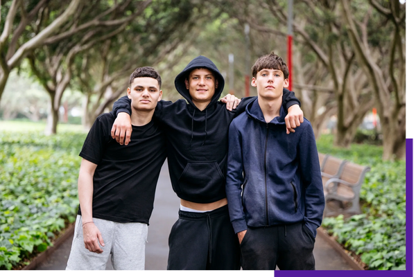 Three young men posing together in casual sportswear outdoors.