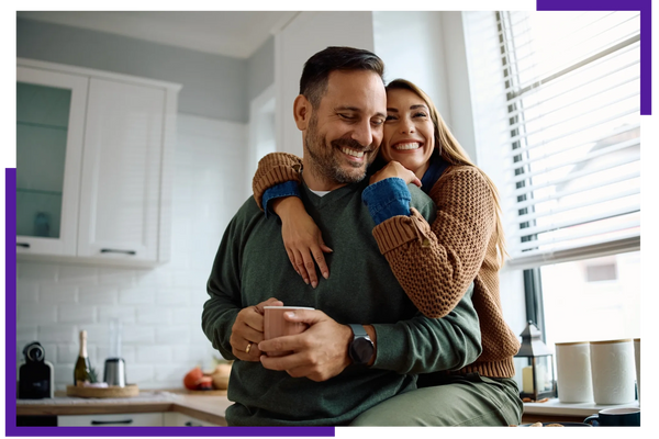Happy couple embracing in a bright kitchen, sharing a cozy moment.
