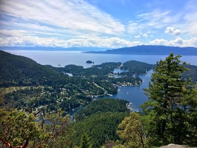 Scenic view of a forested coastline with islands under a partly cloudy sky.