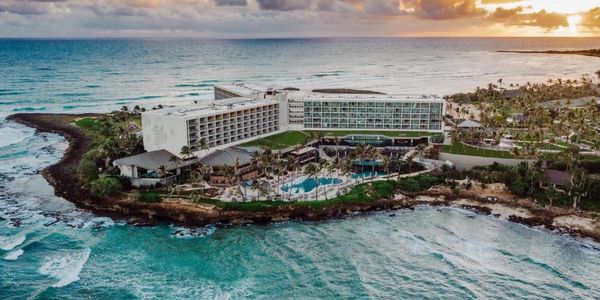 A large resort hotel on a rocky coastline at sunset.