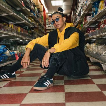 Person in yellow hoodie and sunglasses sitting on grocery store floor.