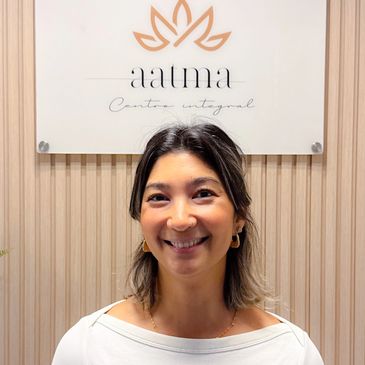 Smiling woman standing in front of a wellness center sign.