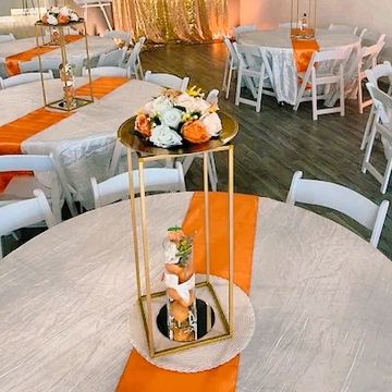 Table centerpiece decor rental option showing floral arrangement on gold metal stand.