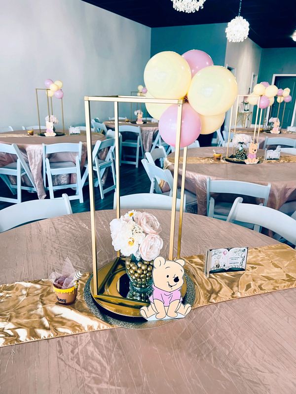Pooh Bear centerpieces in pink and creamy yellow for a baby shower at Suite Events venue .