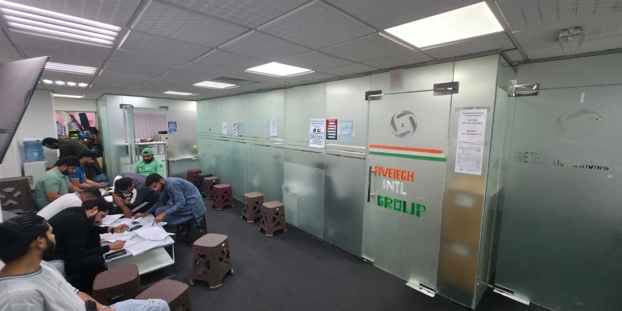 People engaged in paperwork inside an office with frosted glass walls.