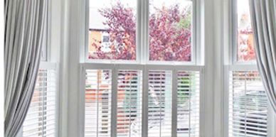White shutters on bay windows with curtains