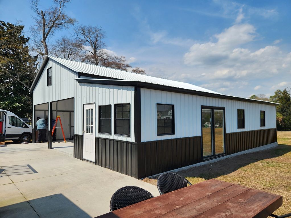 Modern black and white metal building with large windows and sliding doors.