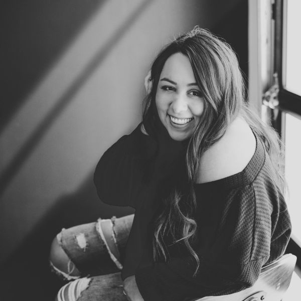 A joyful woman with long hair smiling warmly in black and white.