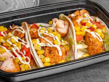 Three salmon tacos with corn and sauce.