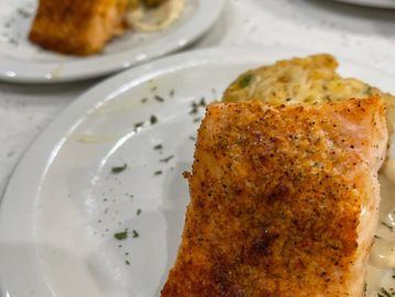 Seasoned cooked salmon fillet with a side dish.
