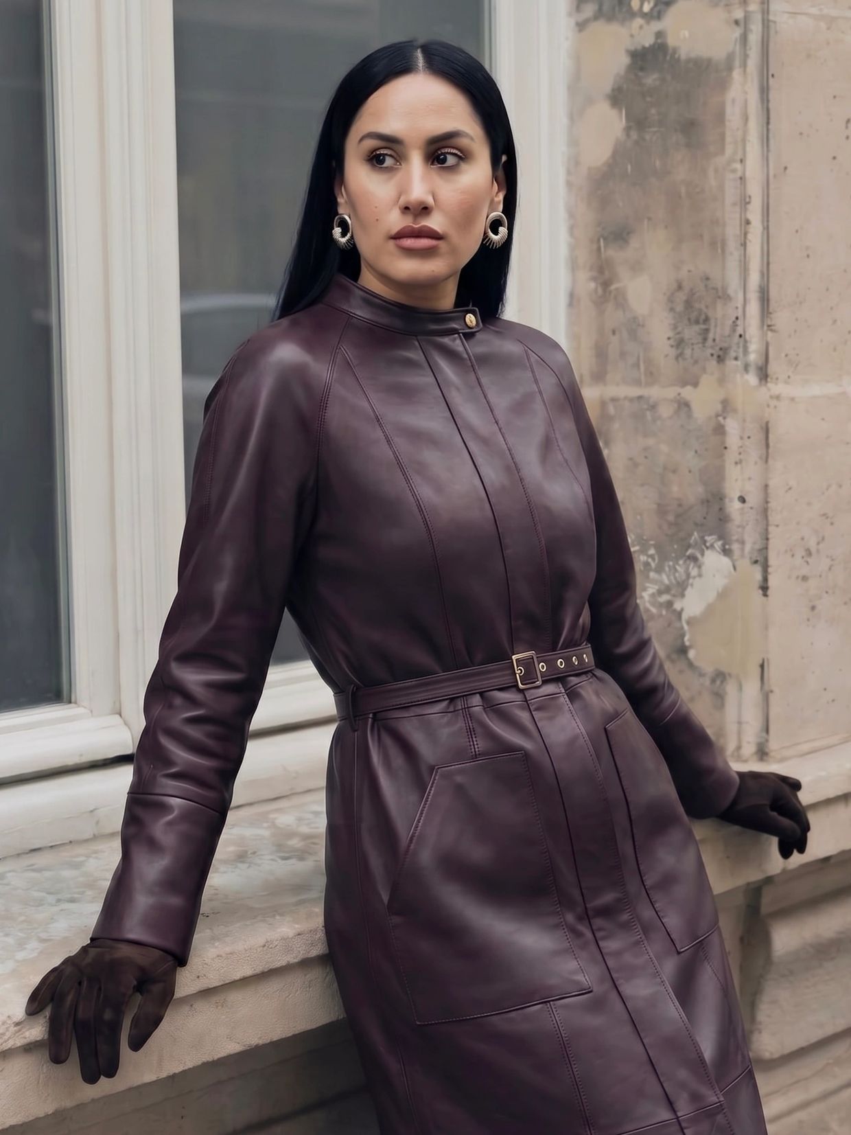 Woman in a purple leather dress and gloves leaning against a window ledge.