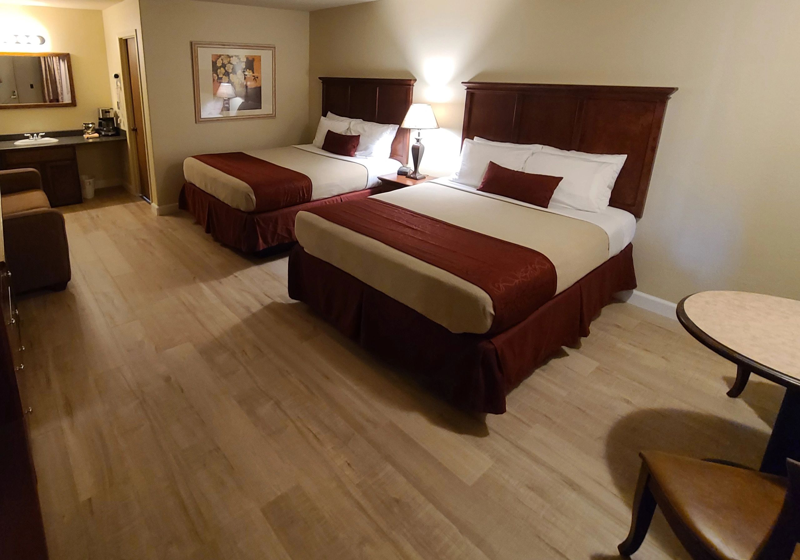 A hotel room with two beds, a desk, and a lamp.
