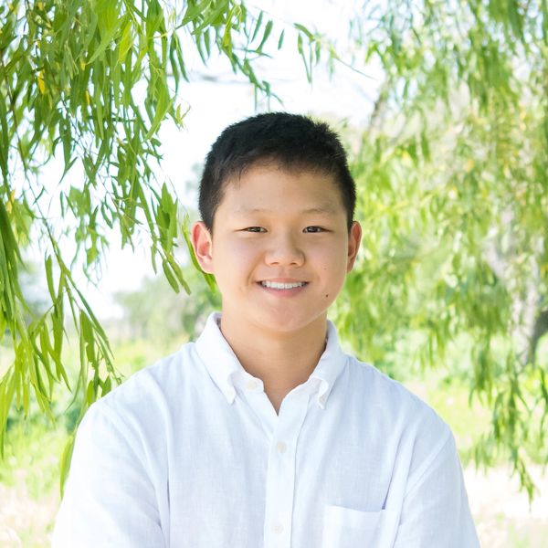 Smiling boy in white shirt outdoors.
