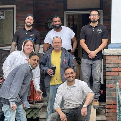 Group of seven people posing casually outside a house.