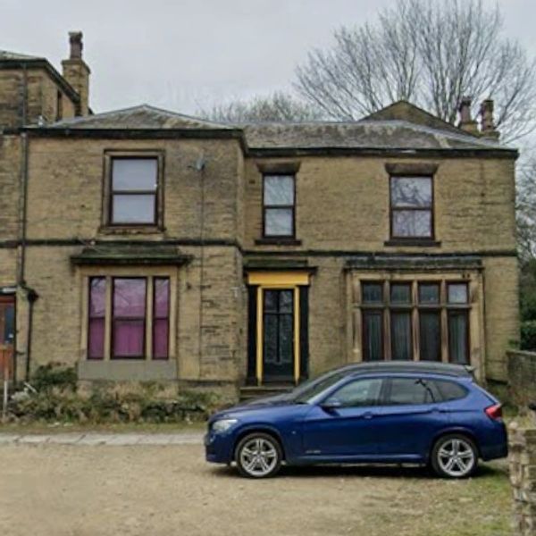 Blue SUV parked in front of a traditional stone house with large windows.
