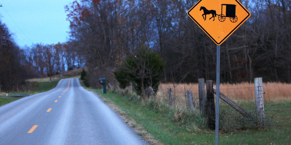 A roadside sign warns drivers to watch for horse and buggy traffic on an empty stretch of highway.