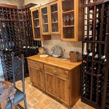 Rustic wine cellar with wooden racks and vintage chairs.
